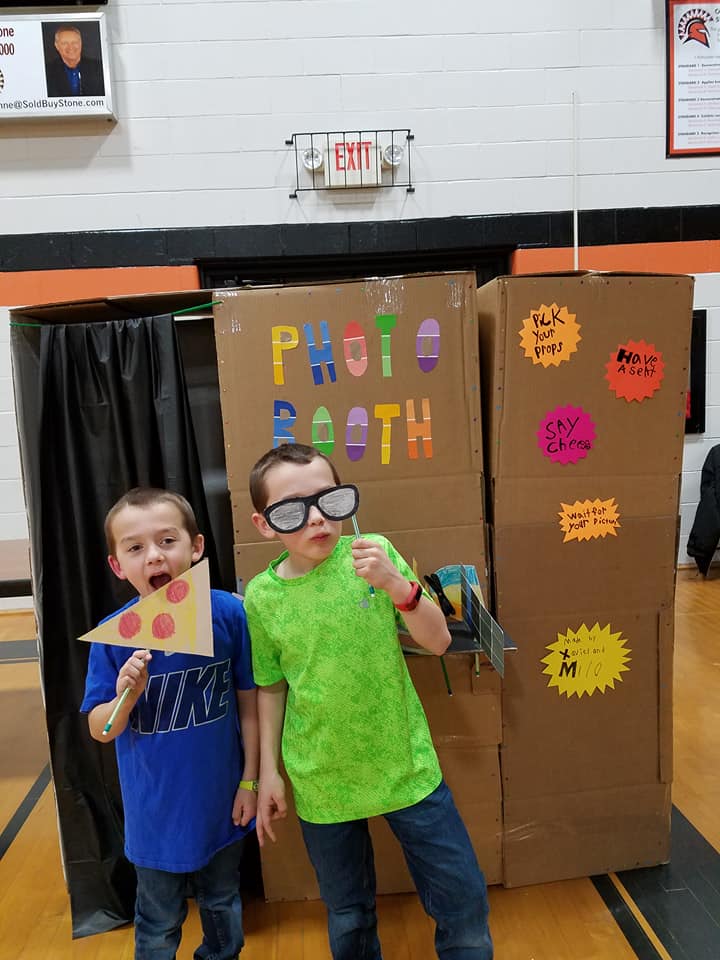 boys standing in front of a recycled material photo booth